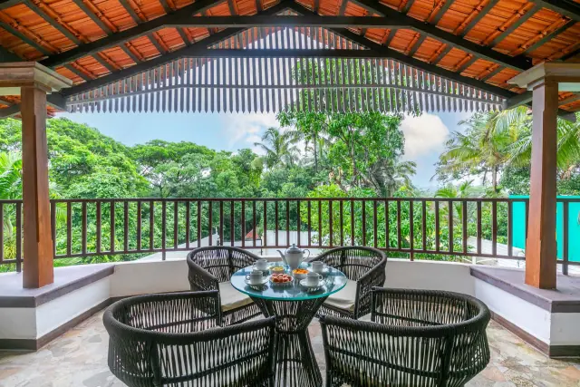 Covered balcony with cane chairs looking into the palms
